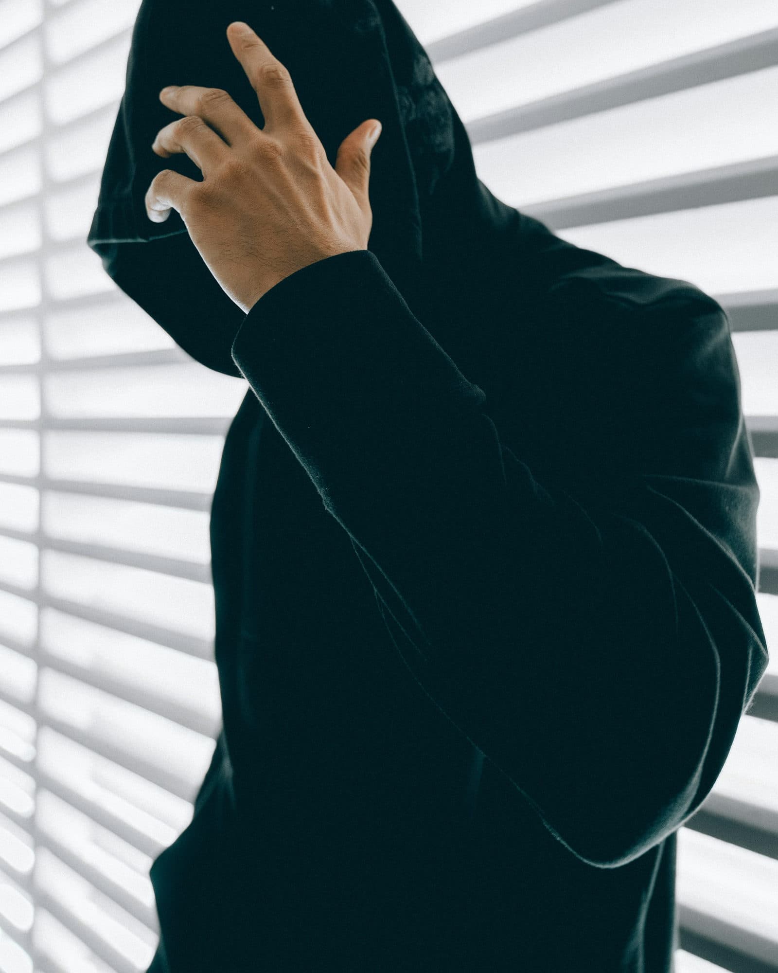 Model in layered streetwear outerwear on a concrete backdrop